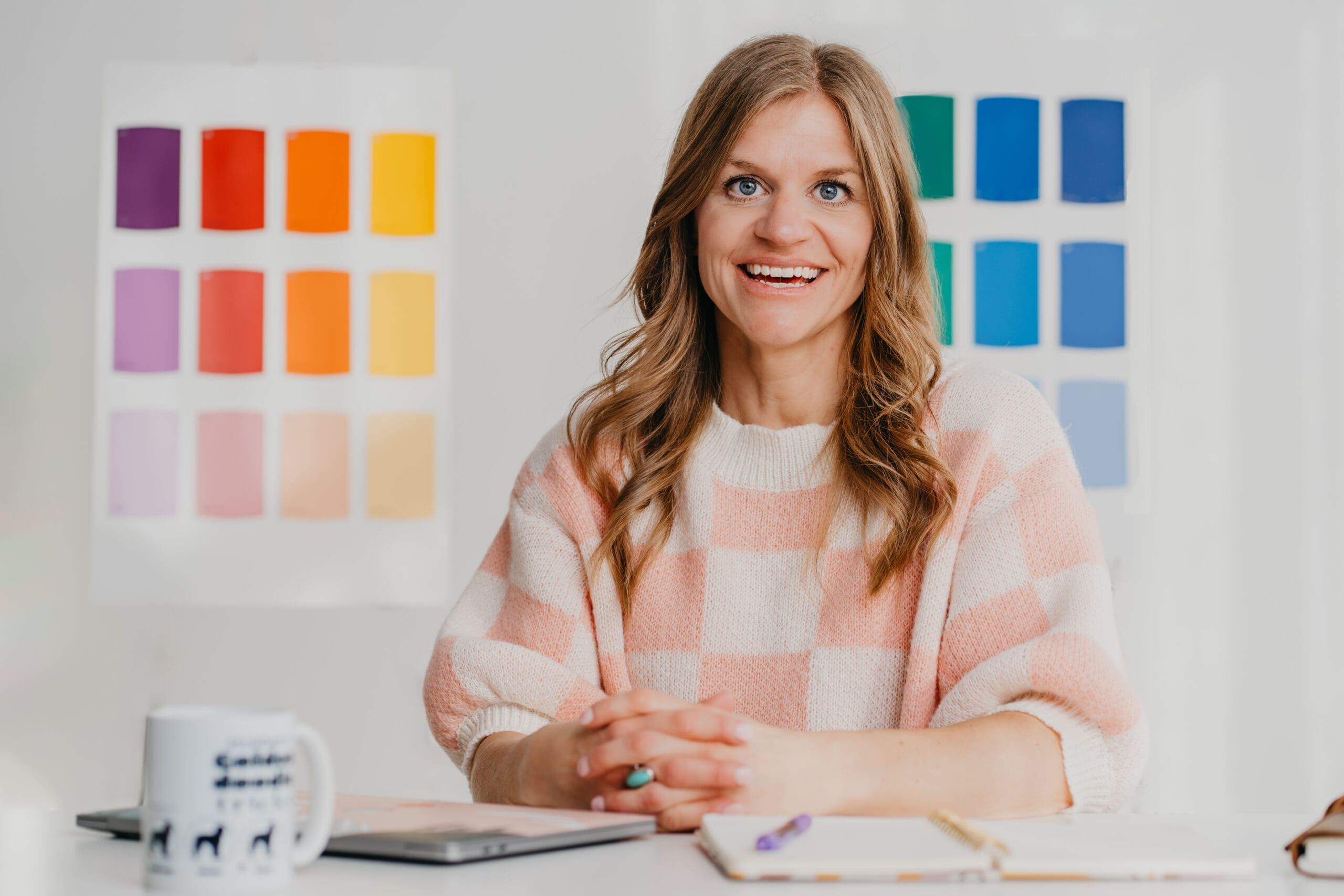 Beth Requist, Wordpress and Showit web designer, Beth sitting at desk in pink and white checkered shirt