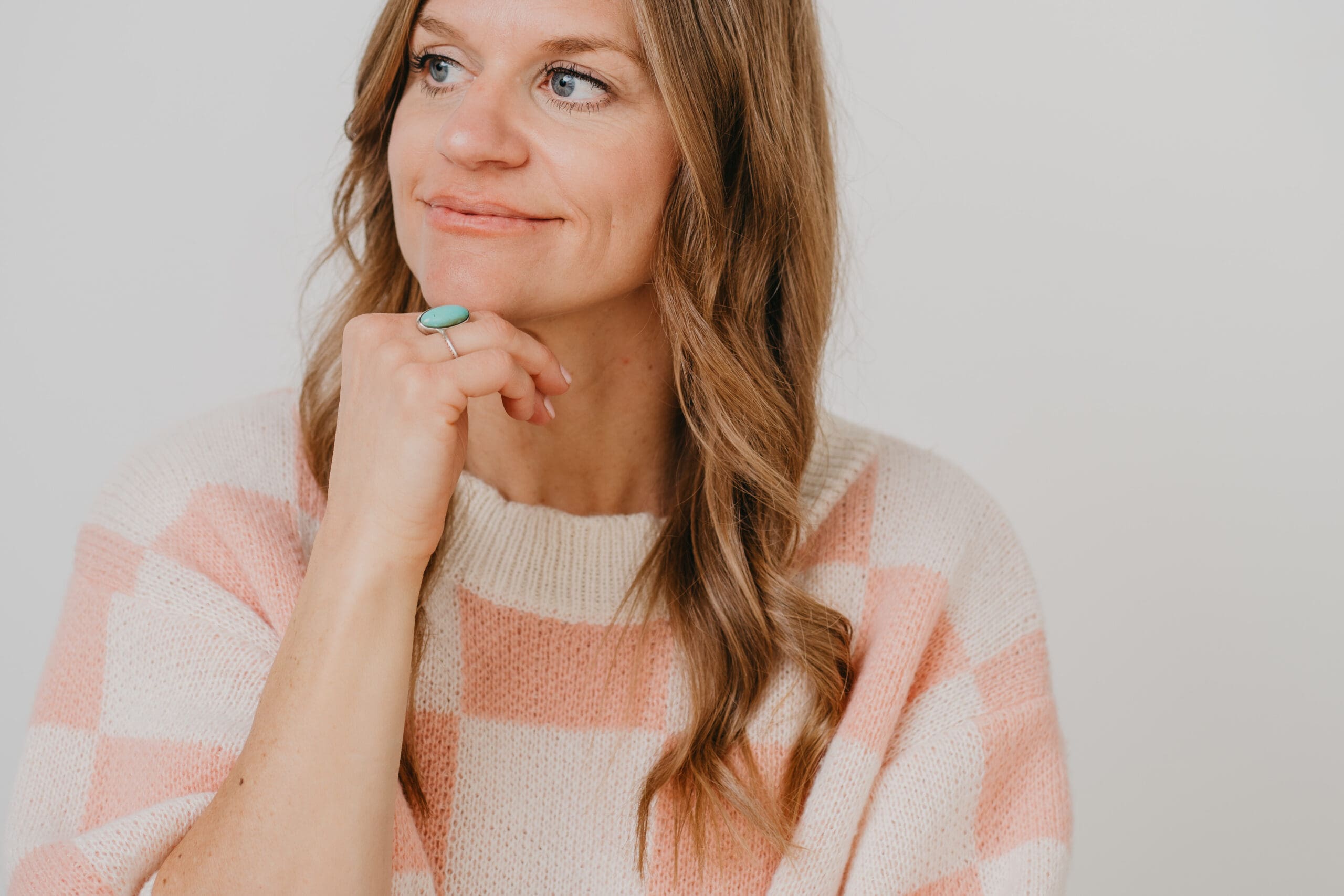headshot of Beth wearing a white and pink checkered sweater